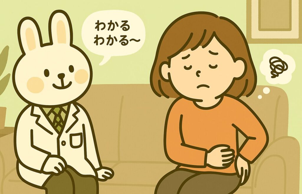 ソファに座るすずちゃんが腰をさすりながら不安そうな表情を浮かべており、隣で白衣を着たうさぎの薬剤師・みどりんが「わかるわかる〜」と優しく声をかけている。背景は室内で、落ち着いた緑と茶色を基調とした空間。